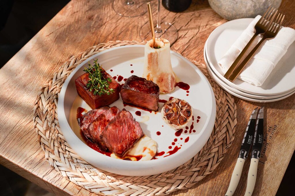 Plate of ribeye with roasted garlic and other accoutrements at Casa Madera in West Hollywood, California. Photo by Valentina Giorcelli.